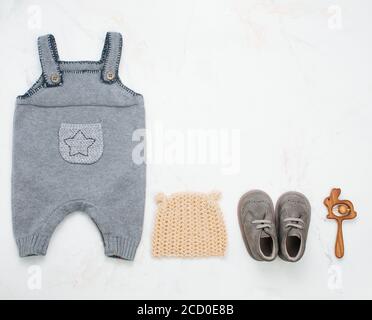 Neugeborene Babykleidung und Sitzsack auf hellem Marmorhintergrund mit Platz für Text. Draufsicht, flach liegend. Stockfoto