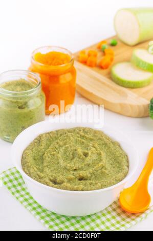 Natürliches Babynahrung Konzept. Verschiedene Arten von Gemüsepüree auf dem hellen Hintergrund neben Zutaten. Stockfoto