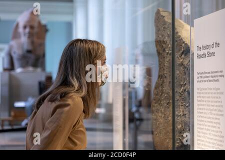 London, England. August 2020. Eine Frau, die eine Gesichtsbedeckung trägt und den Rosetta Stone im British Museum betrachtet. Das British Museum wird seine Türen für die Öffentlichkeit im Einklang mit den Richtlinien der Regierung und mit neuen Sicherheitsmaßnahmen wieder öffnen. Nach fünf Monaten Schließung aufgrund der Coronavirus-Pandemie wird das British Museum am 27. August 2020 seine Pforten wieder für die Öffentlichkeit öffnen. Eine neue Einbahnstraße rund um die Galerien im Erdgeschoss ermöglicht den Besuchern den Zugang zu über 9000 Objekten. Weitere Galerien werden später im September wieder eröffnet. (Foto von Sam Mellish / Alamy Live Ne Stockfoto