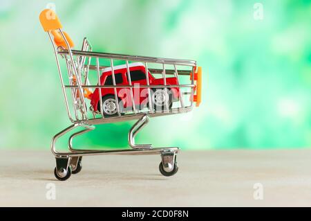 Auto Spielzeug in kleinen Warenkorb über hellgrün verwischen Hintergrund mit leerem Raum für Text. Stockfoto
