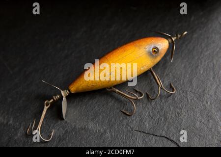 Ein Beispiel für einen alten South Bend Angelköder, oder Stecker, entwickelt, um Raubfische auf einem dunklen Schieferhintergrund angezeigt zu fangen. Aus einer Sammlung von Vin Stockfoto