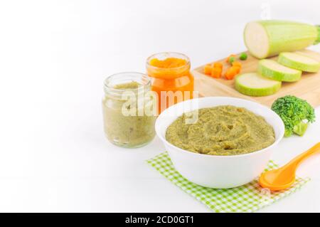 Natürliches Babynahrung Konzept. Verschiedene Arten von Gemüsepüree auf dem hellen Hintergrund in der Nähe von Zutaten mit Leerzeichen für Text Stockfoto
