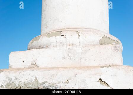 Weiße antike Vintage-Säule in technischem, rissem Stuck. Reparatur der Gebäudesäule. Nahaufnahme. Gegen den blauen Himmel Stockfoto