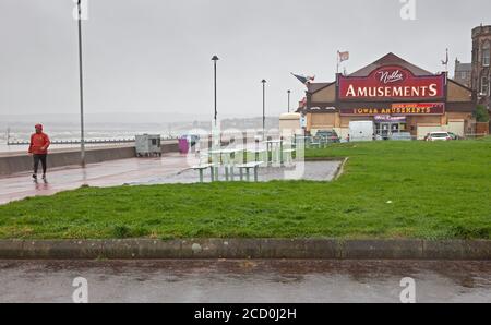 Portobello, Edinburgh, Schottland, Großbritannien. 25. August 2020. Miserable Bedingungen am Meer mit sehr stürmischen Wind und treibenden Regen Komplimente von Storm Francis, halten die meisten Menschen weg von der Küste, aber es gab die seltsam passend gekleideten Fußgänger auf der Promenade zu sehen. Nachdem das Big Ferris Wheel das grüne Licht erst spät am Abend geöffnet hat, liegt es heute wegen des schlechten Wetters geschlossen. Zumindest die Amusement Arcade an der Promenade ist nun nach fünf Monaten der Schließung wegen Covid-19 Einschränkungen geöffnet. Stockfoto