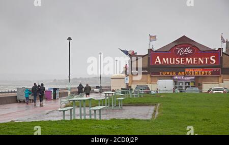 Portobello, Edinburgh, Schottland, Großbritannien. 25. August 2020. Miserable Bedingungen am Meer mit sehr stürmischen Wind und treibenden Regen Komplimente von Storm Francis, halten die meisten Menschen weg von der Küste, aber es gab die seltsam passend gekleideten Fußgänger auf der Promenade zu sehen. Nachdem das Big Ferris Wheel das grüne Licht erst spät am Abend geöffnet hat, liegt es heute wegen des schlechten Wetters geschlossen. Zumindest die Amusement Arcade an der Promenade ist nun nach fünf Monaten der Schließung wegen Covid-19 Einschränkungen geöffnet. Stockfoto