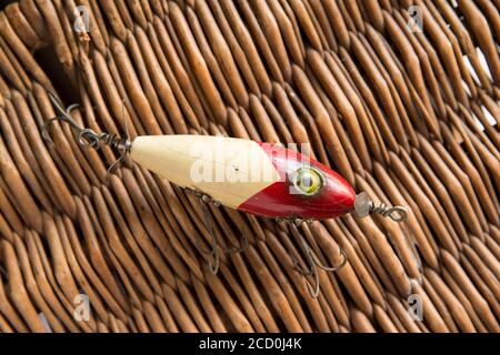 Ein alter South Bend Angelköder, oder Stecker, entwickelt für den Fang Raubfisch fotografiert gegen den whicker Deckel eines alten Tackle Box. Aus einer Sammlung Stockfoto