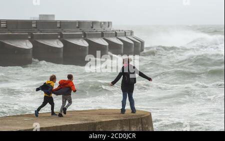 Brighton UK 25. August 2020 - Diese Familie genießt es, wie Wellen über Brighton Marina Westwand bei starken Winden krachen, während Sturm Francis heute durch Großbritannien fegt : Credit Simon Dack / Alamy Live News Stockfoto