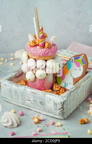 Happy Birthday Party Hintergrund: Freak Shake Topping mit Donut, Marshmallow als Einhorn in der Holzkiste mit Popcorn gefüllt dekoriert; selektiver FOC Stockfoto