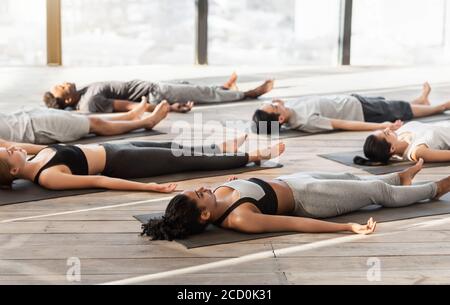 Gruppe von sportlichen Menschen entspannen während Yoga-Unterricht, liegen in Leiche Pose Stockfoto