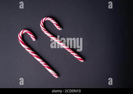 Zwei Neujahrs-Bonbons, auf schwarzem Hintergrund. Minimalistische Komposition, Konzept der Weihnachtsbonbons Stockfoto