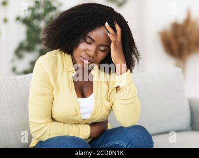 Müde afroamerikanische Frau, die unter Schmerzen leidet Stockfoto