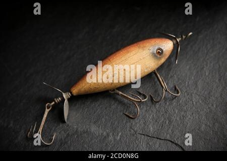 Ein Beispiel für einen alten South Bend Angelköder, oder Stecker, entwickelt, um Raubfische auf einem dunklen Schieferhintergrund angezeigt zu fangen. Entsättigte Farben. Fro Stockfoto