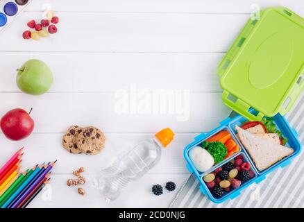 Offene Lunchbox mit Sandwich, Gemüse, Ei, frischen Beeren auf dem weißen Holzhintergrund mit Kopierplatz. Draufsicht, flach liegend. Stockfoto