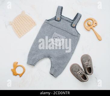 Babykleidung für Neugeborene, Beißring und Sitzsack auf hellem Marmorhintergrund. Draufsicht, flach liegend. Stockfoto