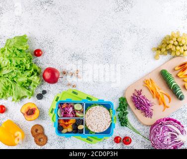 Offene Lunchbox mit Sandwich, Knäckebrot, Obst und Gemüse mit Zutaten Stockfoto