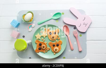 Rosa Teller mit Pfannkuchen auf weißem Holzhintergrund. Draufsicht, flach liegend. Stockfoto