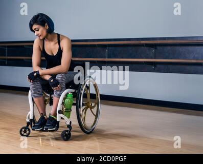 Eine querschnittsgelähmte Frau, die entmutigt aussieht, während sie eine Pause vom Sport in einer Erholungseinrichtung macht: Edmonton, Alberta, Kanada Stockfoto