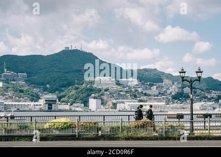 Nagasaki, Kyushu, Japan, Ostasien - Schüler, die nach der Schule nach Hause gehen. Schöne Landschaft von Meer und Berg mit verschiedenen Gebäuden. Stockfoto