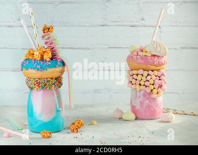 Happy Birthday Party Hintergrund: Zwei Freak Shakes Topping mit Donut, Marshmallow, Bakereien, Popcorn und Marmelade über grauen Backstein Hintergrund; wählen Stockfoto