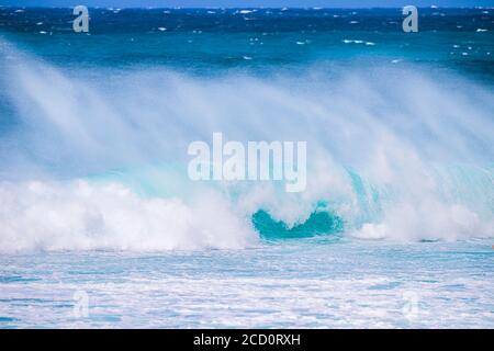 Plätschernden Wellen entlang der Küste mit einem hellen blauen Himmel am Horizont, Banzai Pipeline; Oahu, Hawaii, Vereinigte Staaten von Amerika Stockfoto