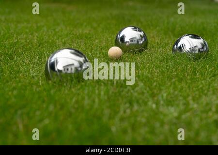 Boccia Kugeln aus verchromtem Stahl liegen auf einer Grasfläche. Spielen Sie für Ihren eigenen Garten. Stockfoto