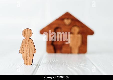 Hölzerne weibliche Figur vor dem Haus auf weißem Hintergrund als Symbol für Probleme in Familienbeziehungen. Konzentrieren Sie sich auf weibliche Figur, Leerzeichen für Text Stockfoto