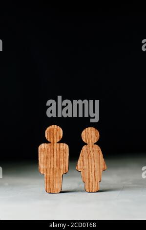 Holzfiguren von Mann und Frau auf schwarzem Hintergrund mit Leerzeichen für Text. Stockfoto