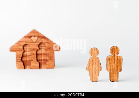Männliche und weibliche Holzfiguren vor dem Haus auf weißem Hintergrund. Konzentrieren Sie sich auf paar Zahlen, Leerzeichen für Text. Stockfoto