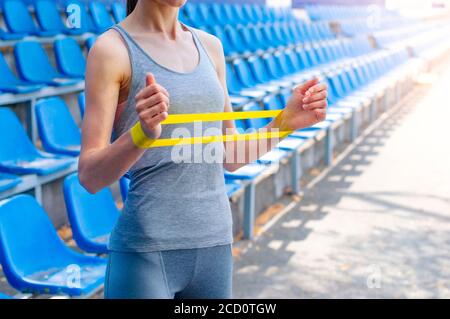 Junge Frau macht ihre Übungen mit Fitness-Gummiband auf Stadion, selektive Fokus Stockfoto
