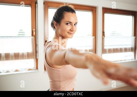 Portrait der sportlichen jungen Frau in Kriegerpose Yoga üben Zu Hause Stockfoto