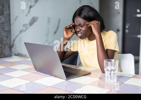 Traurig deprimiert junge gemischte Rasse weiblich sitzen am Küchentisch mit Papieren und Laptop, müde besorgt Blick, massieren Augen während der Berechnung fam Stockfoto