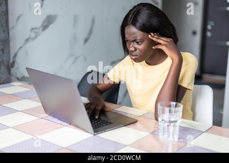 Traurig deprimiert junge gemischte Rasse weiblich sitzen am Küchentisch mit Papieren und Laptop, müde besorgt Blick, massieren Augen während der Berechnung fam Stockfoto