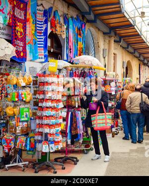 Larnaca, ZYPERN - 16. FEBRUAR 2020: Souvenirmarkt für Touristen im Pavillon, Menschen, die in Reihe zwischen Geschäften mit Waren laufen Stockfoto