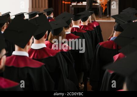 Gruppe von frischen Hochschulabsolventen mit Roben und Mützen in Diplomfeier Stockfoto