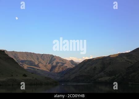 der mond steigt in der Abenddämmerung über dem Oxbow-Damm in idaho auf Stockfoto