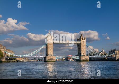 Tower Bridge weiten Blick Landschaft mit roten Londoner bus überqueren die Brücke und den Fluss Themse, gesehen von einem RB1 Pendler River Boat am späten Nachmittag Sonne. Southwark London UK Panorama Vista Stadtblick Attraktion mit klaren blauen Himmel. Die Tower Bridge ist eine kombinierte Klapp- und Hängebrücke in London, zwischen 1886 und 1894 gebaut. Die Brücke überquert den Fluss Themse in der Nähe des Tower von London und hat eine Ikone und bleibendes Symbol der London England Großbritannien UK werden Stockfoto