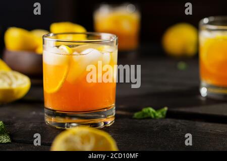 Kaltes Getränk von Zitrone Eistee auf dunklem Hintergrund. Ein erfrischendes Sommergetränk aus frisch gepresster Zitrone, gemischt mit kaltem schwarzem Tee, Eis und Zucker. Stockfoto