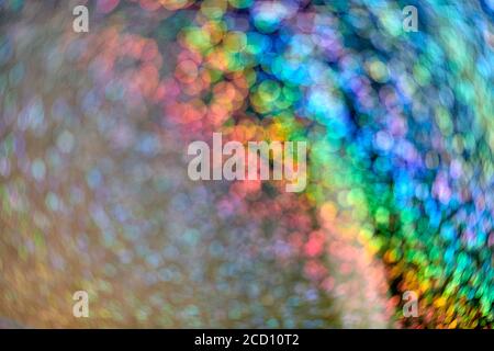 Regenbogen funkeln Glitzer. Abstrakter Hintergrund. Bunt leuchtende Regenbogentropfen und Lichter auf schwarzem Hintergrund. Festlich glänzender Glitzer von verschwommenen Pailletten und Stockfoto