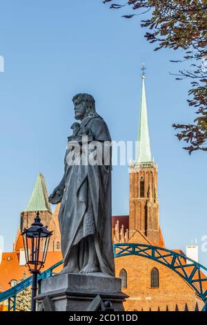 Statue des heiligen Johannes des Täufers auf der Tumski-Brücke mit der Kirche des Heiligen Kreuzes (Stiftskirche des Heiligen Kreuzes und des heiligen Bartholomäus) im ... Stockfoto