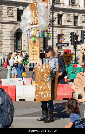 Ein Mann, der während des Klimastreiks, Parliament Square, London, 20. September 2019, Schilder und Plastikgegenstände hochhält Stockfoto