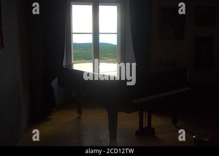 Ein luxuriöses schwarzes Klavier an einem offenen Fenster Stockfoto