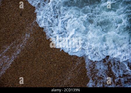 Meereswelle trifft auf den Sand. Blick von oben. Nahaufnahme für Textur Stockfoto