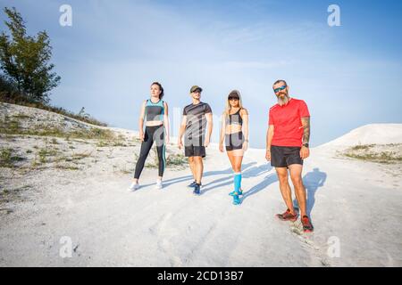 Gruppe von Läufern, die vor dem Trailrunning-Training im Freien stehen. Weitwinkelansicht mit langen Schatten Stockfoto