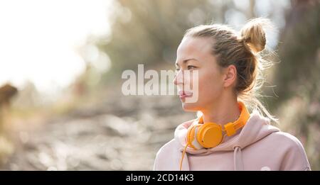 Porträt einer schönen Sportfrau mit Hoodie und Kopfhörern während des Trainings im Freien. Stockfoto