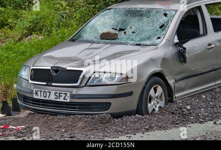 Ein verlassenes, zerstörtes Auto mit zertrümmerten Windschutzscheiben und fehlenden Fenstern Stockfoto