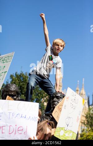 Ein kleiner Junge, der auf einer Außenplastik steht und während des Klimabrekes, London, 20. September 2019, die Faust hebt Stockfoto