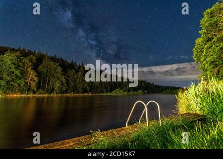 Idylic Nachthimmel - die Milchstraße über dem klaren See in der Nacht mit den Reflexen. Stockfoto