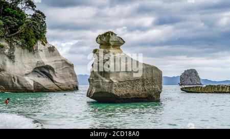 Die berühmte Cathedral Cove ist nur zu Fuß oder mit dem Boot erreichbar und gehört zu den Sehenswürdigkeiten auf dem Coromandel. Schwimmer genießen den Strand und spielen in... Stockfoto