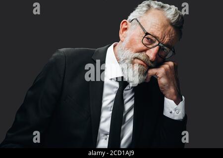 Traurige reife Geschäftsmann mit müden Augen und erfahrenen Gesichtsausdruck Denken mit der Hand über das Kinn isoliert auf schwarz Stockfoto