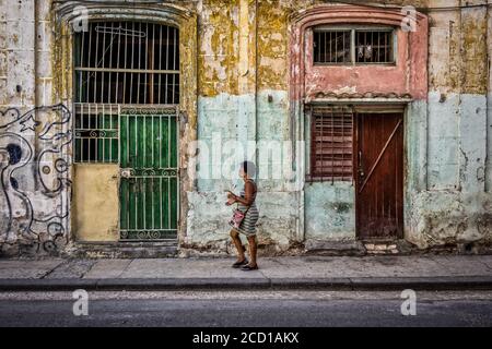 Havanna, Kuba, Juli 2019, Frau, die vor einem baufälligen Gebäude in der Altstadt läuft Stockfoto